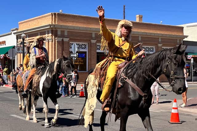 Bill Williams Mountain Men in buckskins and fur hats riding horses in a parade through downtown Williams, one waving